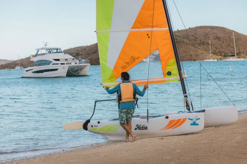 Grace Yacht Photos Pics Person with sailboat on beach, Aquila 54 in background.