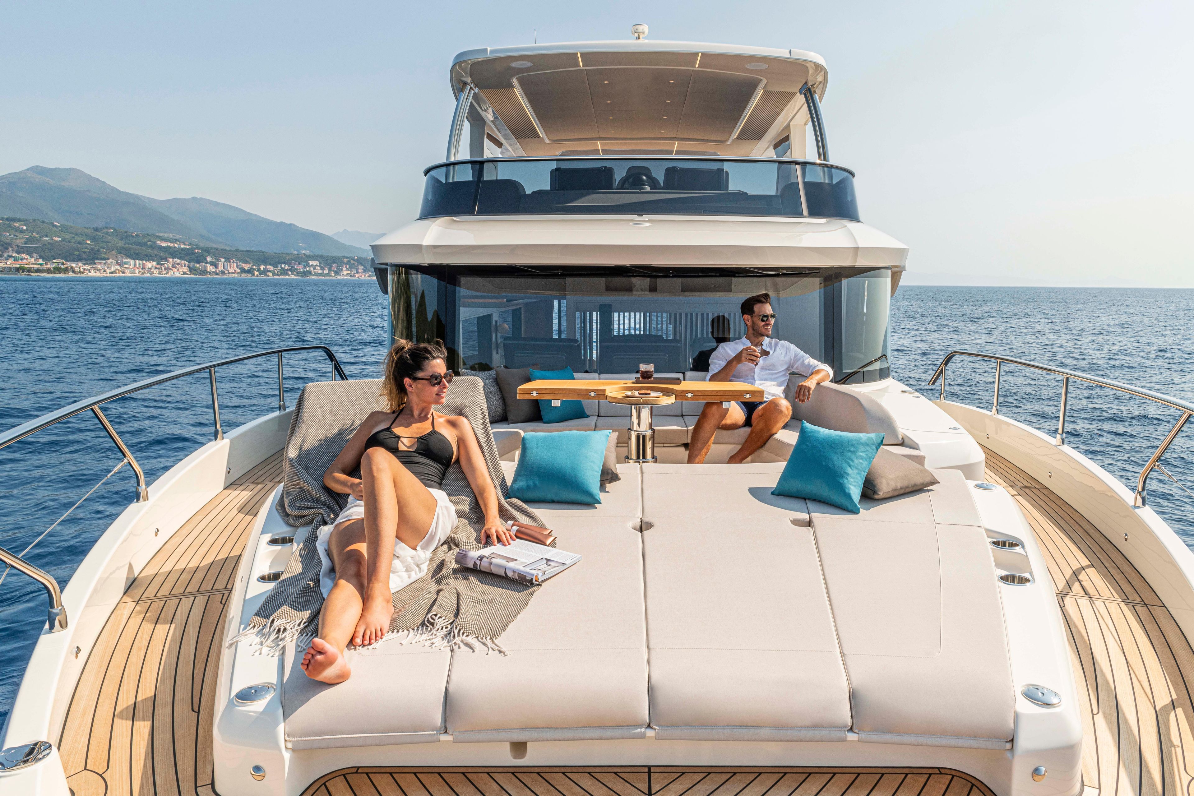 Couple relaxing on Absolute 70 N yacht, 2026 model, enjoying sunny sea views.