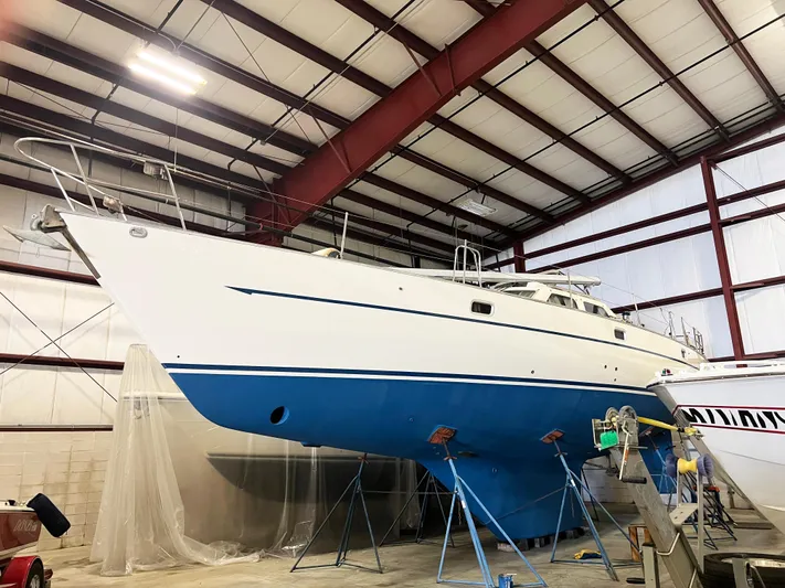 Here Be Dragons Yacht Photos Pics 1987 Oyster 46.5 sailboat in a warehouse, elevated on stands for maintenance.