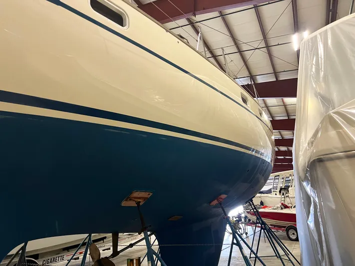 Here Be Dragons Yacht Photos Pics Oyster 46.5 sailboat from 1987 in indoor storage, blue and white hull.