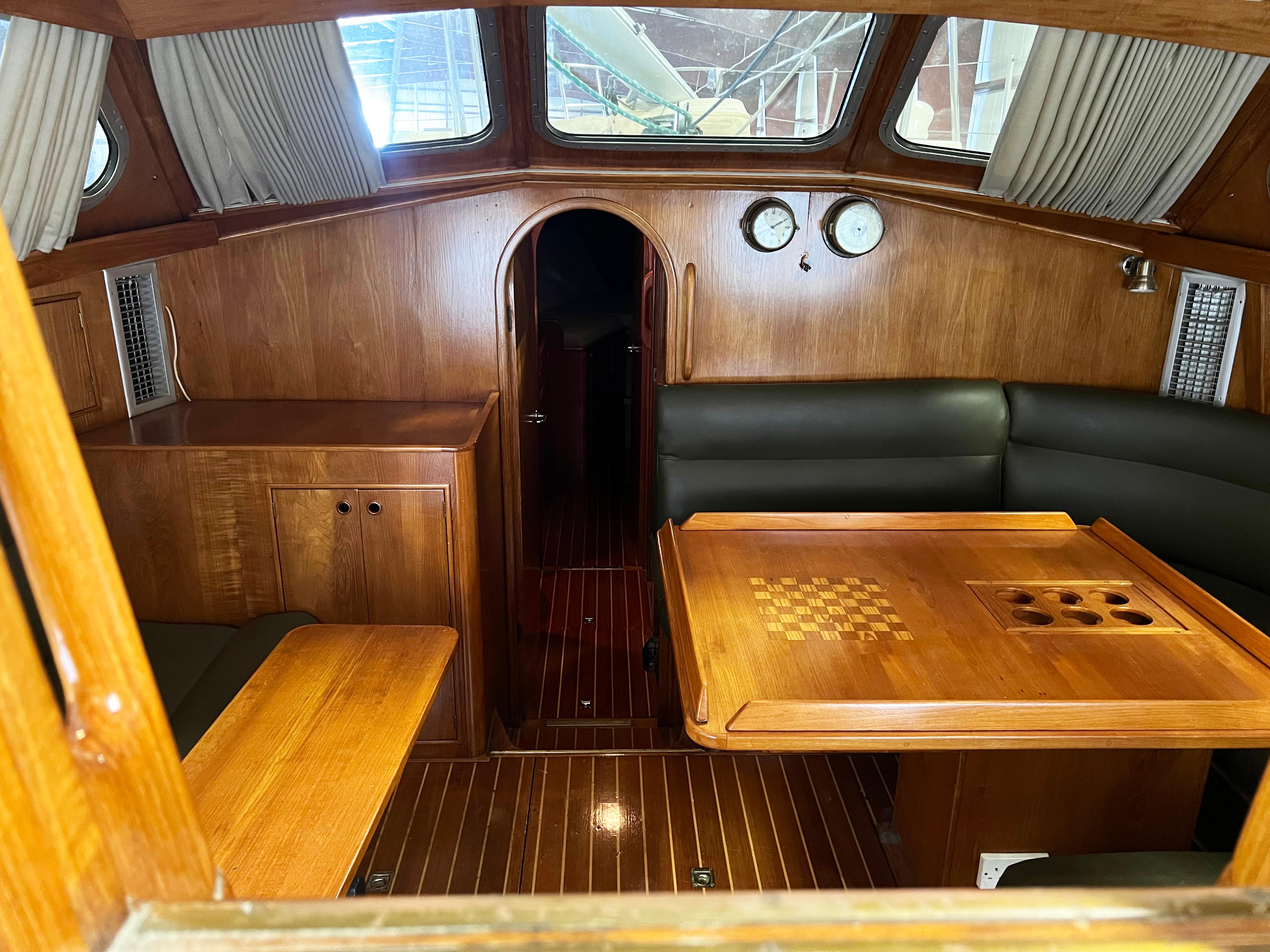 Interior of 1987 Oyster 46.5 yacht with wooden furnishings and seating area.