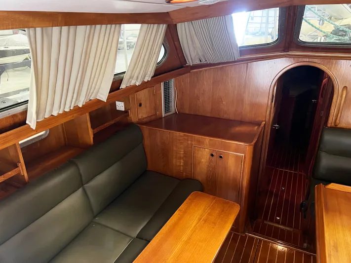 Here Be Dragons Yacht Photos Pics Interior of 1987 Oyster 46.5 yacht with wood finish and leather seating.