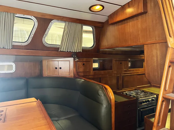Here Be Dragons Yacht Photos Pics Interior of 1987 Oyster 46.5 yacht with wood paneling and cozy seating area.