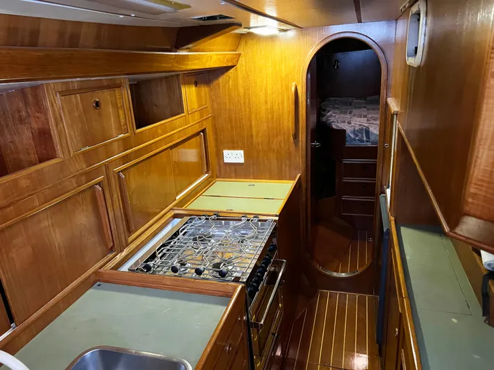 Here Be Dragons Yacht Photos Pics Interior of 1987 Oyster 46.5 yacht with wooden cabinetry and compact kitchen.