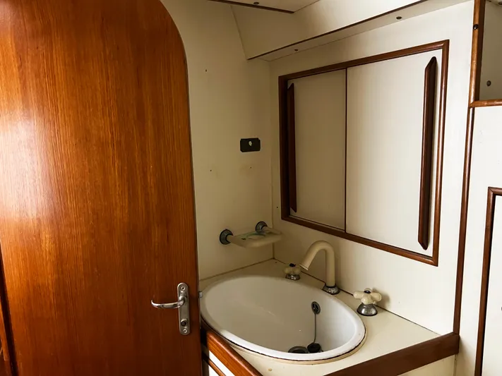 Here Be Dragons Yacht Photos Pics Interior of 1987 Oyster 46.5 yacht bathroom with wooden door and sink.