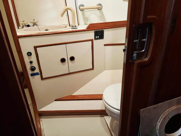 Here Be Dragons Yacht Photos Pics 1987 Oyster 46.5 yacht bathroom with sink, toilet, and wooden accents.