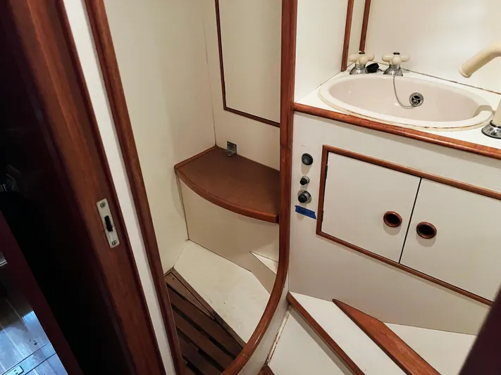 Here Be Dragons Yacht Photos Pics Interior of 1987 Oyster 46.5 yacht bathroom with sink and wooden accents.