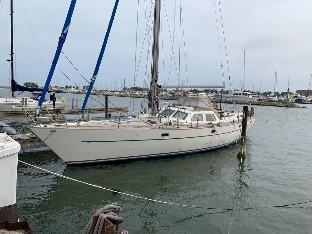 1987 Oyster 46.5 sailboat docked in a marina, calm waters, overcast sky.