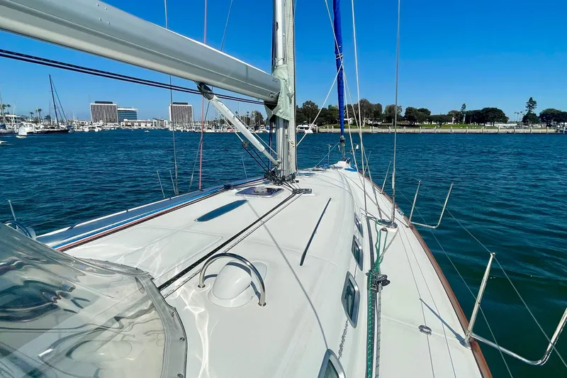 Caravan Yacht Photos Pics 2003 Beneteau First 47.7 sailboat on calm waters, clear sky, marina in background.
