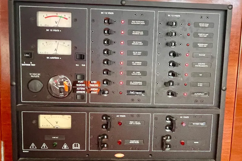 Caravan Yacht Photos Pics Electrical control panel of a 2003 Beneteau First 47.7 sailboat, featuring various switches and gauges.