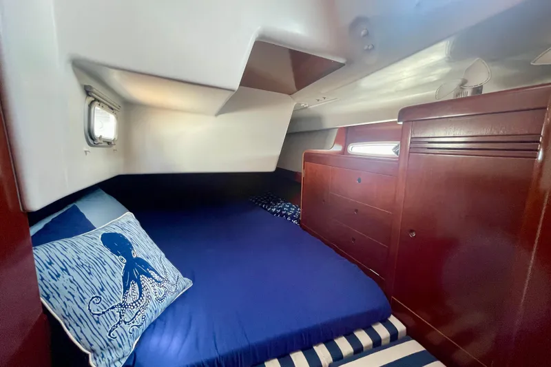 Caravan Yacht Photos Pics Cozy cabin interior of 2003 Beneteau First 47.7 yacht with blue bedding and wooden cabinetry.