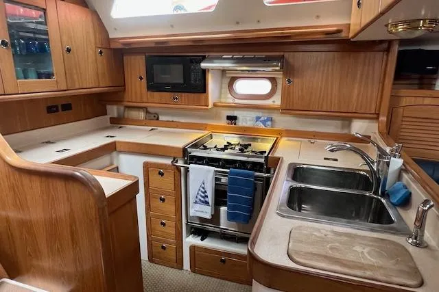 Optimistic Yacht Photos Pics Interior of 2003 Catalina 470 Sloop, featuring a well-equipped kitchen with wooden cabinetry.