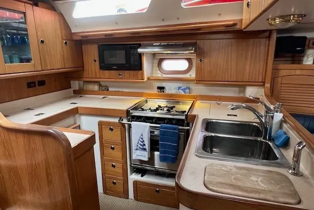 Optimistic Yacht Photos Pics Interior of 2003 Catalina 470 Sloop, featuring a well-equipped kitchen with wooden cabinetry.