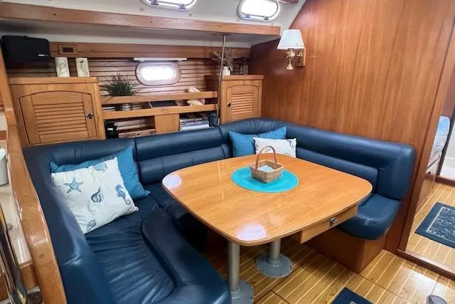 Optimistic Yacht Photos Pics Interior of 2003 Catalina 470 Sloop, featuring a cozy dining area with blue seating.