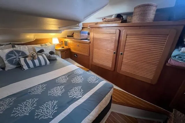 Optimistic Yacht Photos Pics Cozy cabin interior of 2003 Catalina 470 Sloop with wing keel, featuring wooden cabinets and nautical bedding.