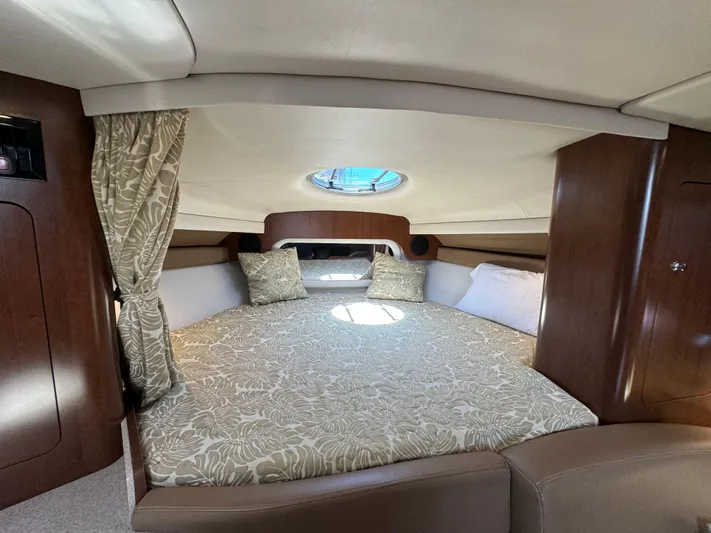  Yacht Photos Pics 2018 Crownline 350 SY cabin interior with bed, wood paneling, and round window.