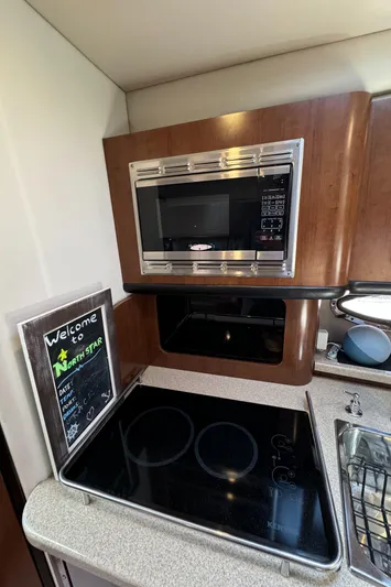  Yacht Photos Pics 2018 Crownline 350 SY kitchen with microwave, stovetop, and welcome sign.