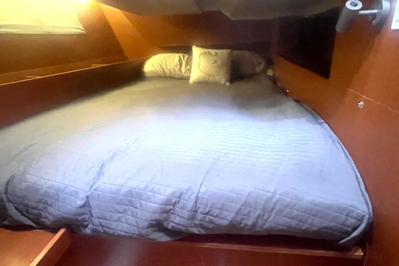 Danmark Yacht Photos Pics Cozy cabin bed in 2019 Beneteau Oceanis 41.1 sailboat, featuring wooden interior and soft bedding.