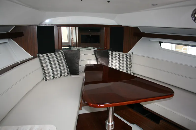 Skye Boat Yacht Photos Pics 2020 Pursuit OS 355 Offshore cabin interior with plush seating and wooden table.
