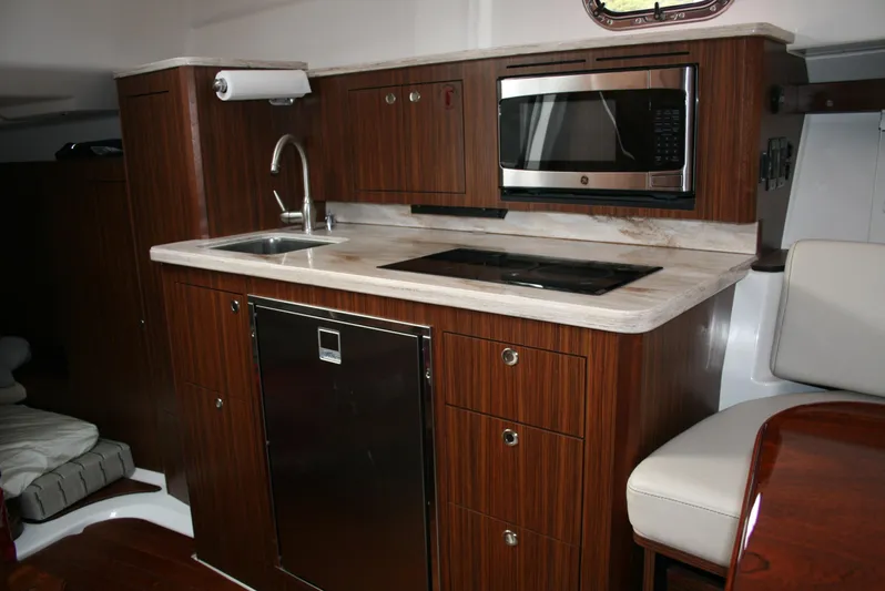 Skye Boat Yacht Photos Pics 2020 Pursuit OS 355 Offshore yacht kitchen with wood cabinetry, sink, and microwave.