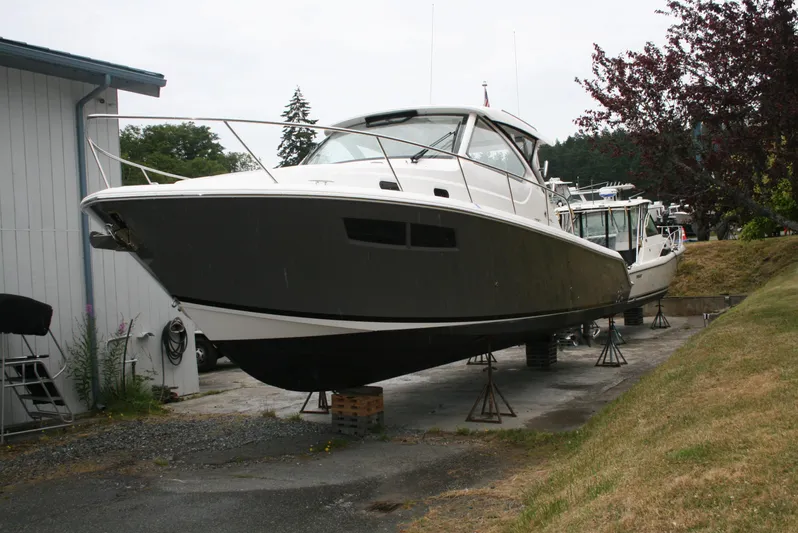 Skye Boat Yacht Photos Pics 2020 Pursuit OS 355 Offshore boat on stands, side view, near a building.