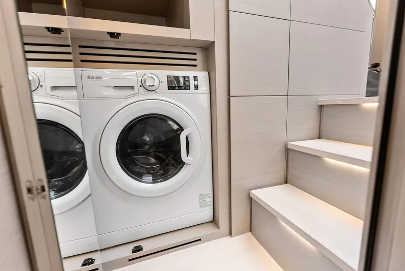 Barnext Yacht Photos Pics Compact laundry area with a washing machine beside modern stairs on a Pershing 7X yacht.