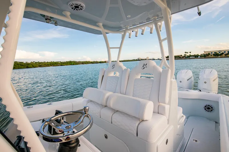 New Stock Yacht Photos Pics 2026 Yellowfin 36 Offshore boat interior with white seating and steering wheel on calm water.