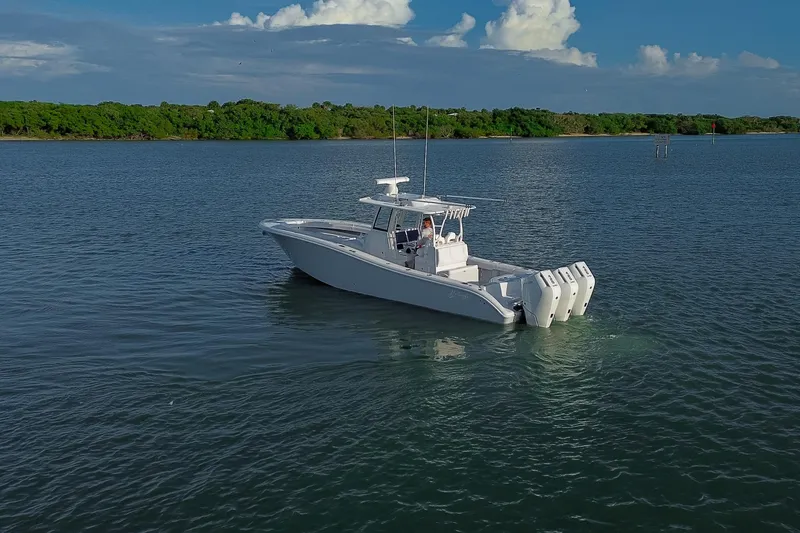 New Stock Yacht Photos Pics 2026 Yellowfin 36 Offshore boat on calm water with lush green shoreline.