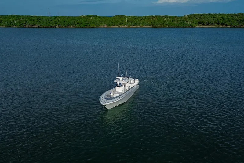 New Stock Yacht Photos Pics 2026 Yellowfin 36 Offshore boat cruising on calm waters near lush green shoreline.
