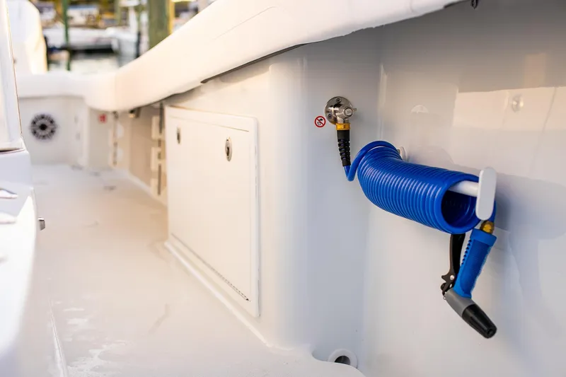 New Stock Yacht Photos Pics 2026 Yellowfin 36 Offshore boat deck with coiled blue hose and storage compartment.