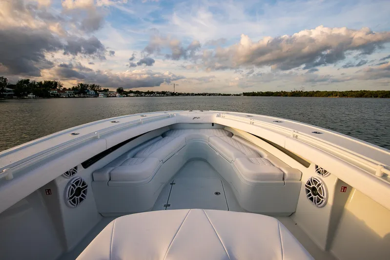 New Stock Yacht Photos Pics 2026 Yellowfin 36 Offshore boat interior with white seating, on calm water under a cloudy sky.