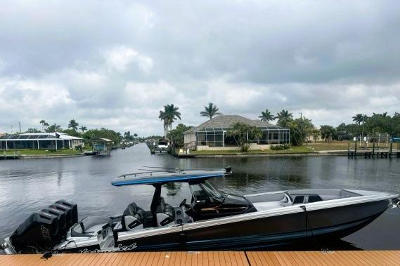 2025 Nor-Tech 400 Supersport boat docked by a scenic waterfront with palm trees.