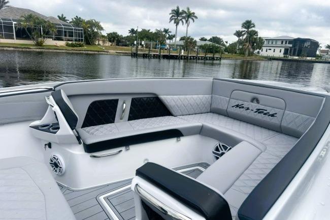 2025 Nor-Tech 400 Supersport boat interior with luxurious seating by a scenic waterfront.