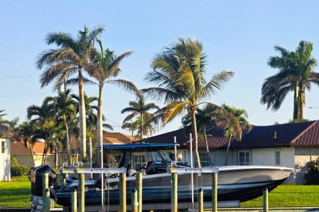 2025 Nor-Tech 400 Supersport boat docked, surrounded by palm trees and waterfront homes.