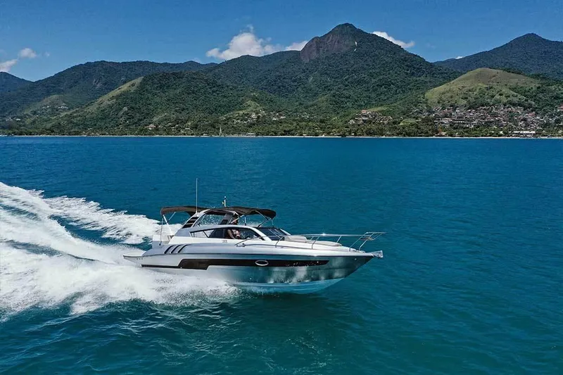 Custom Order Yours Today! Yacht Photos Pics 2025 Hanover 305 Inboard cruising on blue ocean with scenic mountain backdrop.