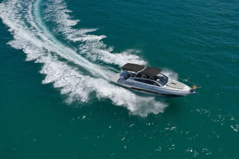 Custom Order Yours Today! Yacht Photos Pics 2025 Hanover 305 Inboard boat cruising on clear blue water, leaving a white wake trail.
