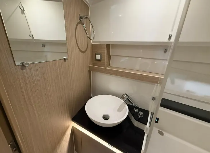  Yacht Photos Pics Modern bathroom interior of 2025 Jeanneau Leader 9.0 WA boat, featuring sleek sink and mirror.