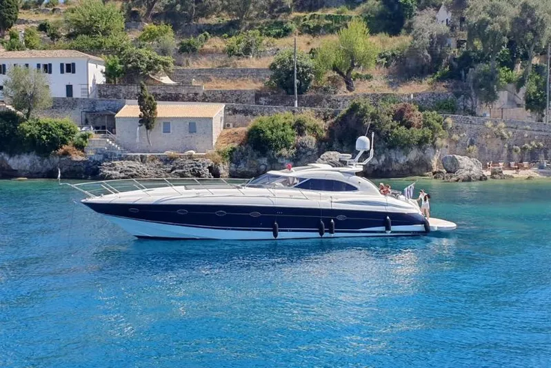  Yacht Photos Pics Sunseeker Predator 56 yacht from 2000 on clear blue water near a scenic coastline.