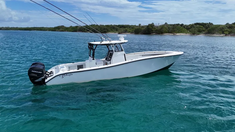  Yacht Photos Pics 2017 Yellowfin 36 Offshore boat on clear blue water near a lush shoreline.
