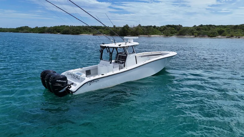  Yacht Photos Pics 2017 Yellowfin 36 Offshore boat on clear blue water near a lush shoreline.