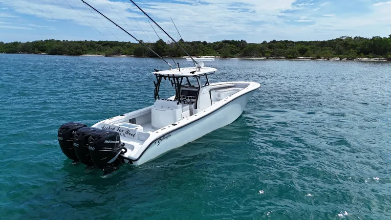  Yacht Photos Pics 2017 Yellowfin 36 Offshore boat on clear blue water near a forested shoreline.