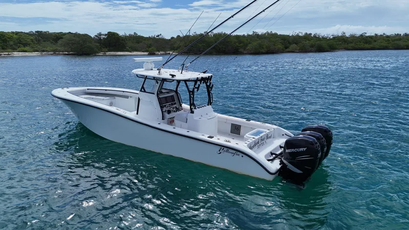  Yacht Photos Pics 2017 Yellowfin 36 Offshore boat on clear blue water near a lush shoreline.