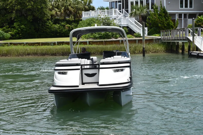  Yacht Photos Pics 2024 Bennington 27 QFB pontoon boat on water near a dockside house.