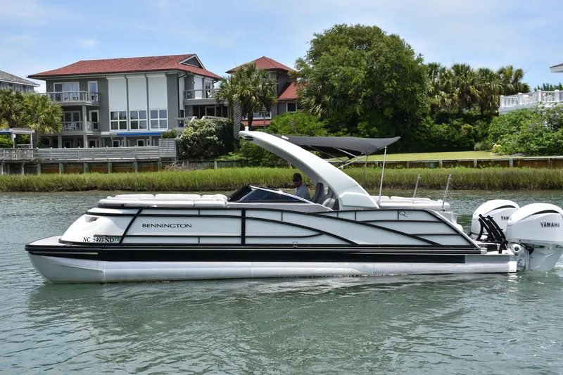 Yacht Photos Pics 2024 Bennington 27 QFB pontoon boat on water, with modern houses in the background.