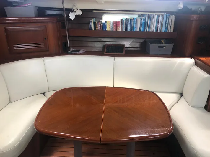 Picaro Yacht Photos Pics Cozy interior of 2005 Beneteau Oceanis 473 sailboat with white seating and wooden table.