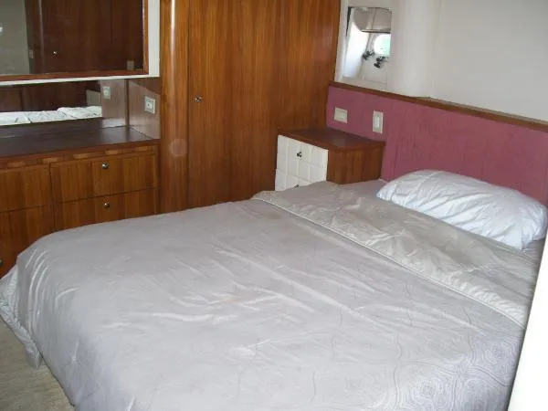  Yacht Photos Pics Bedroom interior of 1999 Bayliner 5788 Pilot House Motoryacht with wooden cabinetry and cozy bed.