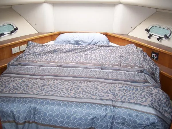  Yacht Photos Pics Cozy bedroom in 1999 Bayliner 5788 Pilot House Motoryacht with patterned bedding and porthole windows.