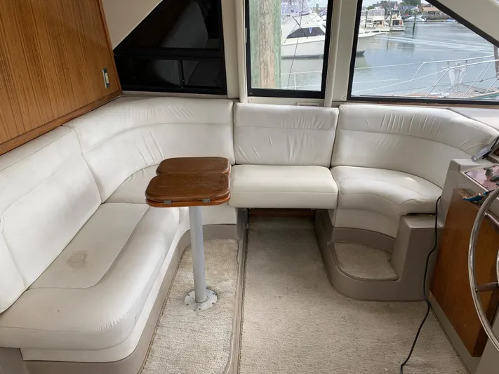  Yacht Photos Pics 1999 Bayliner 5788 Pilot House Motoryacht interior with white leather seating and wooden table.