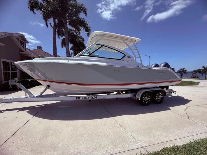  Yacht Photos Pics 2020 Pursuit DC 266 Dual Console boat on trailer, parked near palm trees and house.