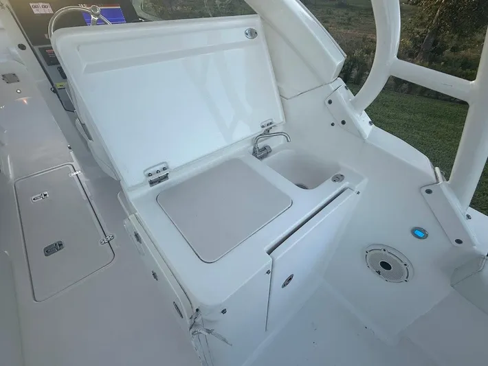  Yacht Photos Pics 2020 Pursuit DC 266 Dual Console boat interior with open storage compartment and sink.